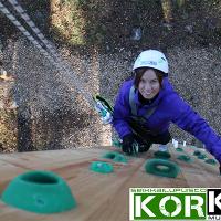 Nainen nousemassa kiipeilyseinää Seikkailupuisto Korkeessa