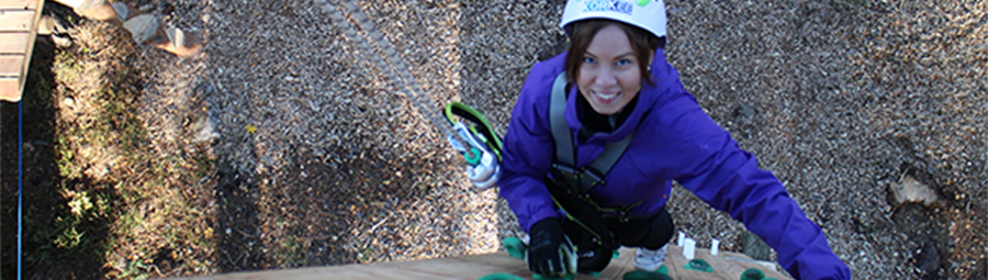 Seikkailija nousemassa kiipeilyseinää Seikkailupuisto Korkeessa